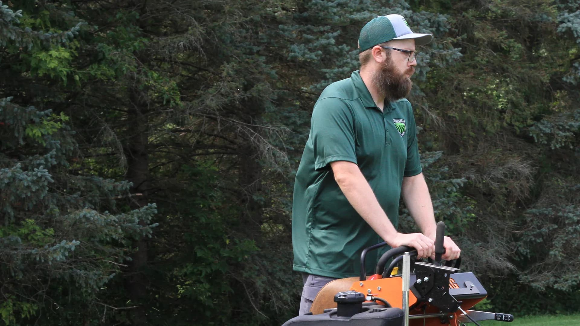 Chris operating a commercial stand-on mower in profile across a mown lawn